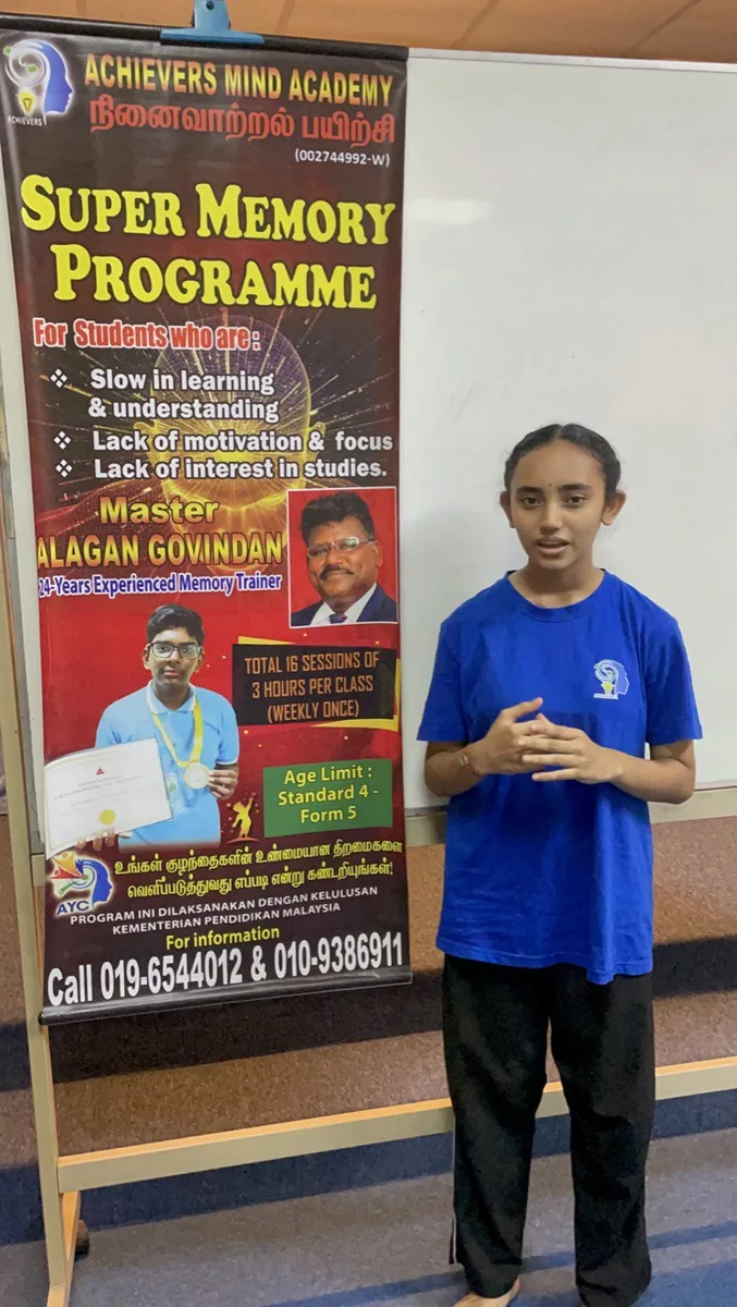 AMA student beside a Super Memory Programme banner